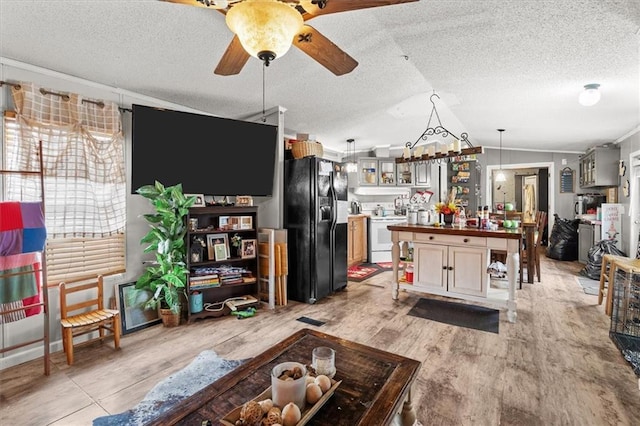 living room featuring ornamental molding, a ceiling fan, a textured ceiling, light wood-style floors, and lofted ceiling