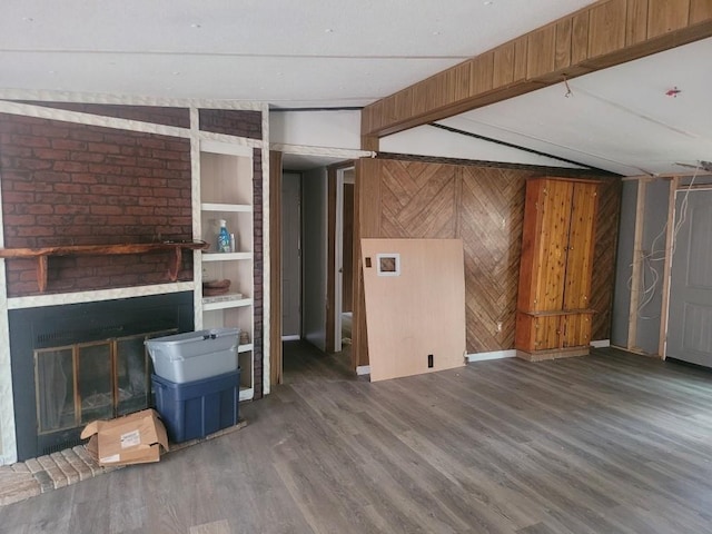 unfurnished living room featuring vaulted ceiling with beams, a fireplace, wood finished floors, and wooden walls