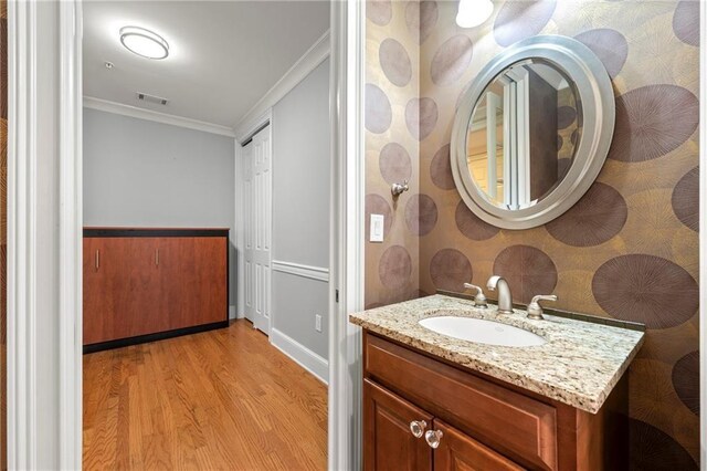 bathroom with crown molding, vanity, and hardwood / wood-style flooring