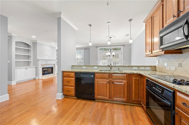 kitchen with light wood-type flooring, ornamental molding, sink, black appliances, and hanging light fixtures