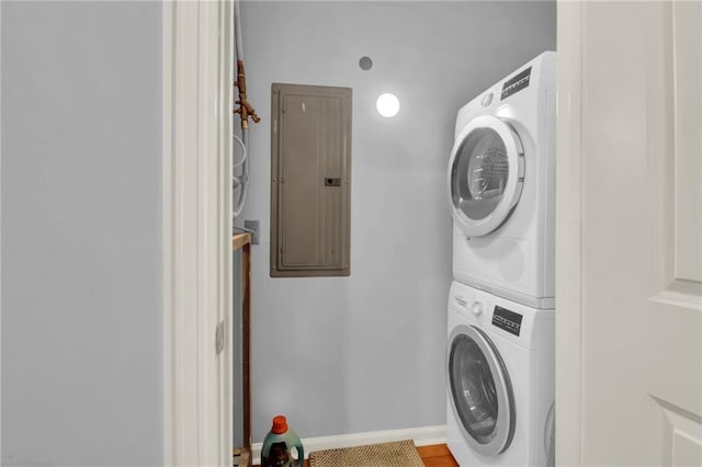 laundry area featuring electric panel and stacked washer / dryer