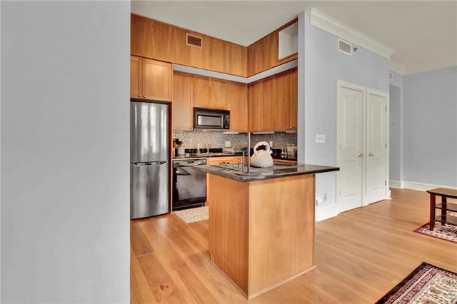 kitchen featuring light wood-type flooring, tasteful backsplash, crown molding, and black appliances