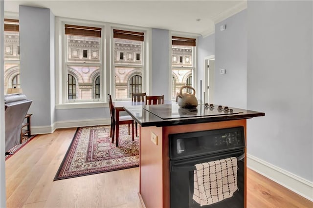 kitchen with black appliances, light wood-type flooring, and ornamental molding