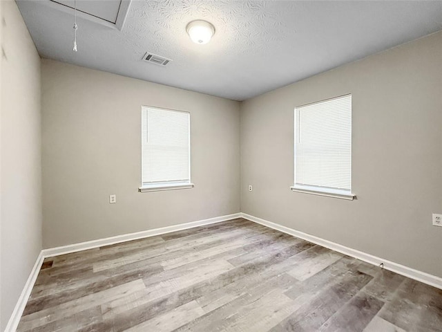 unfurnished room with hardwood / wood-style floors and a textured ceiling