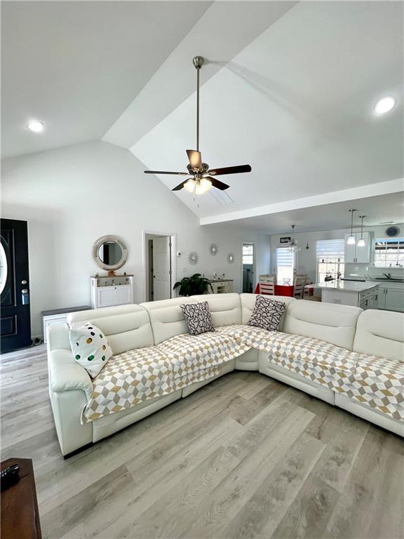 living room featuring a ceiling fan, light wood finished floors, and high vaulted ceiling