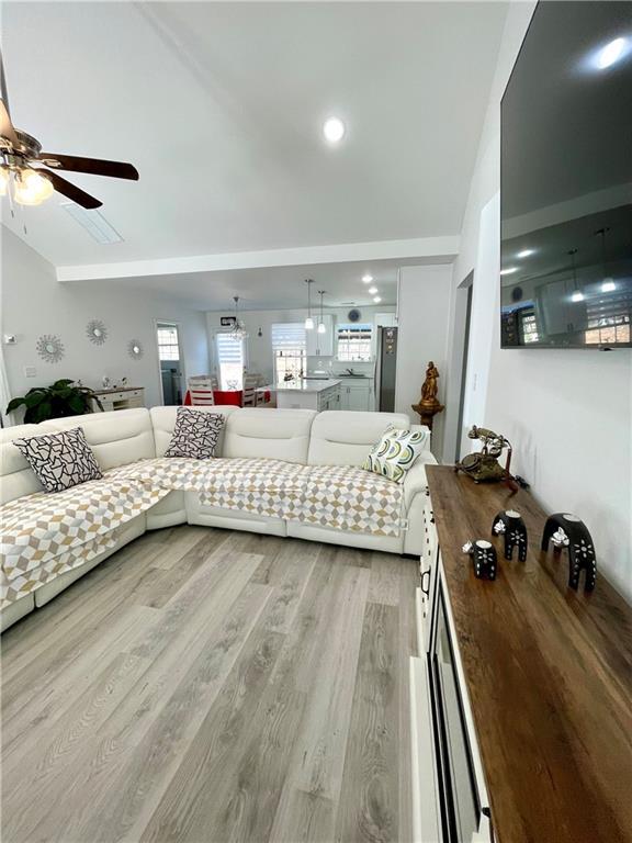 living room featuring lofted ceiling, light wood-type flooring, and ceiling fan