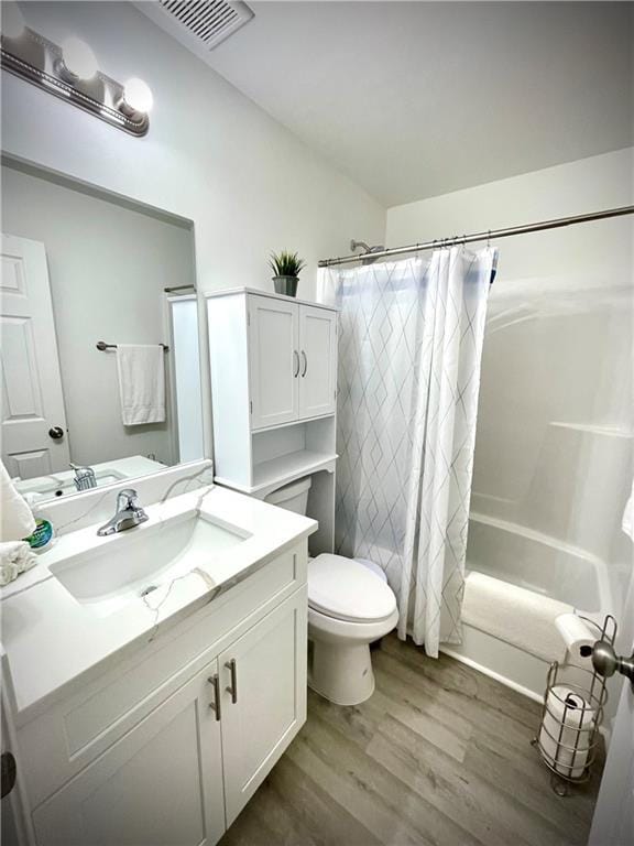 full bathroom featuring visible vents, shower / bath combo with shower curtain, toilet, wood finished floors, and vanity