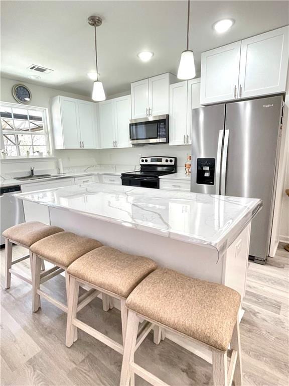 kitchen featuring light wood finished floors, visible vents, appliances with stainless steel finishes, white cabinetry, and a sink