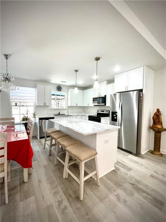 kitchen featuring a kitchen island, stainless steel appliances, light countertops, and light wood-style floors