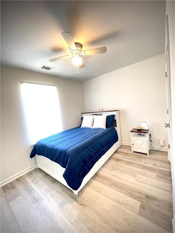 bedroom with visible vents, a ceiling fan, baseboards, and wood finished floors