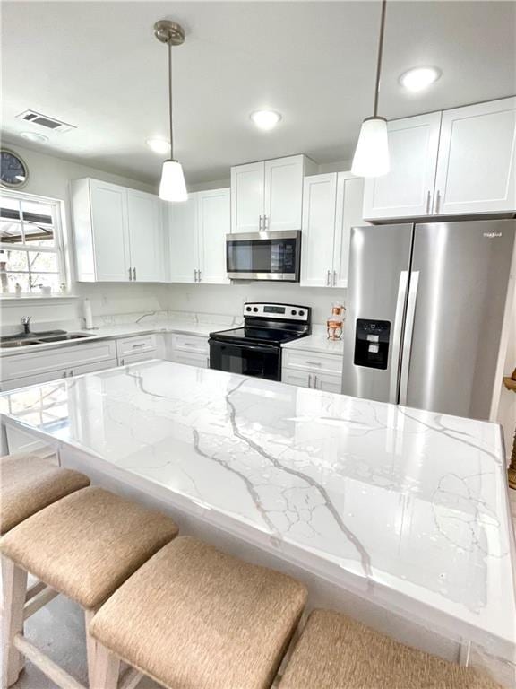 kitchen with visible vents, a sink, white cabinetry, appliances with stainless steel finishes, and light stone countertops