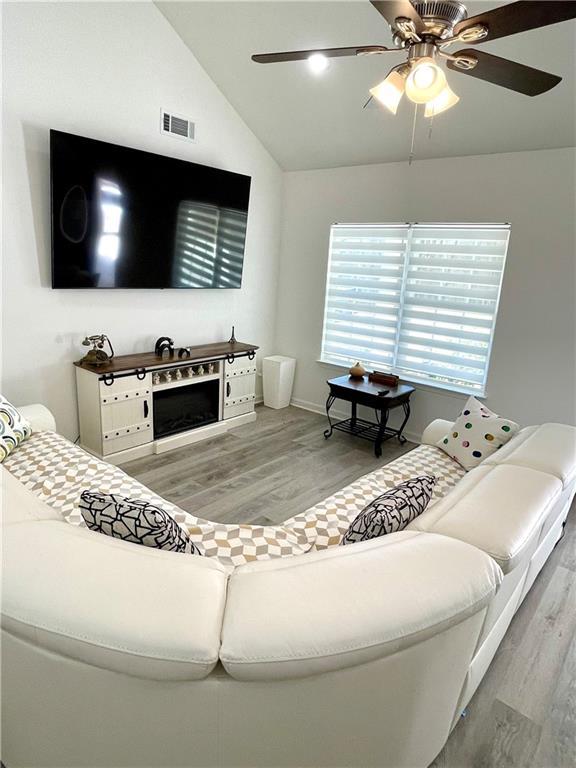 living room featuring visible vents, lofted ceiling, wood finished floors, and a fireplace