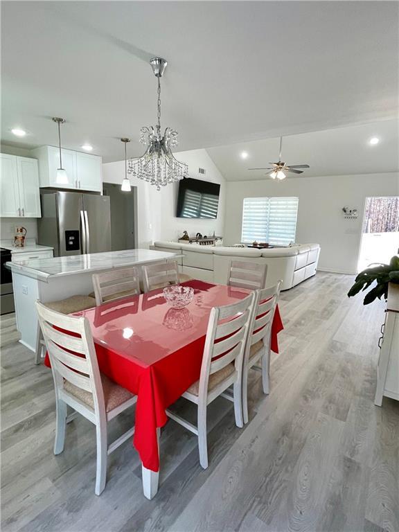 dining room with lofted ceiling, a healthy amount of sunlight, and light wood finished floors