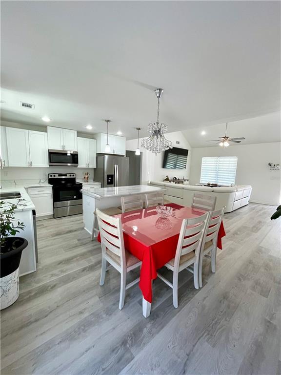 dining area featuring visible vents, a ceiling fan, recessed lighting, light wood finished floors, and vaulted ceiling