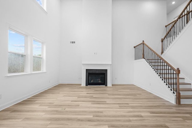 unfurnished living room with a high ceiling and light wood-type flooring