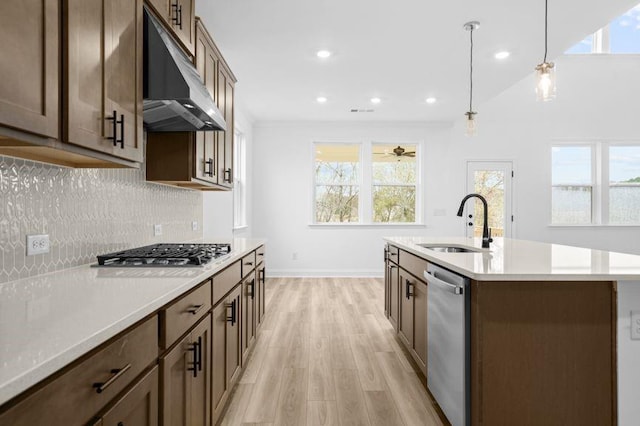 kitchen featuring sink, light hardwood / wood-style flooring, pendant lighting, a center island with sink, and appliances with stainless steel finishes