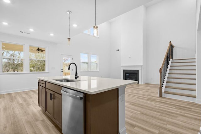 kitchen with stainless steel dishwasher, ceiling fan, sink, pendant lighting, and an island with sink