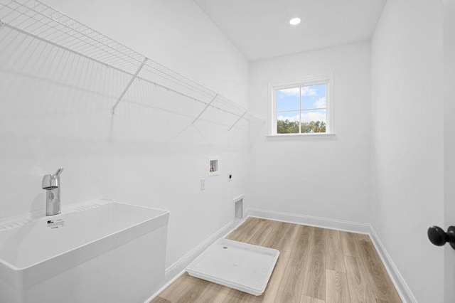 laundry area with hookup for an electric dryer, washer hookup, hardwood / wood-style floors, and sink