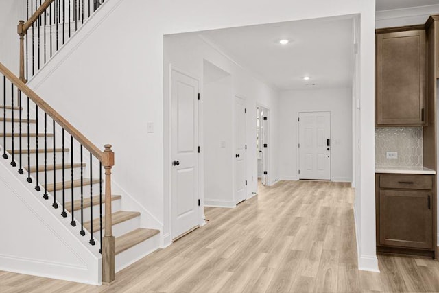 corridor featuring ornamental molding and light hardwood / wood-style flooring