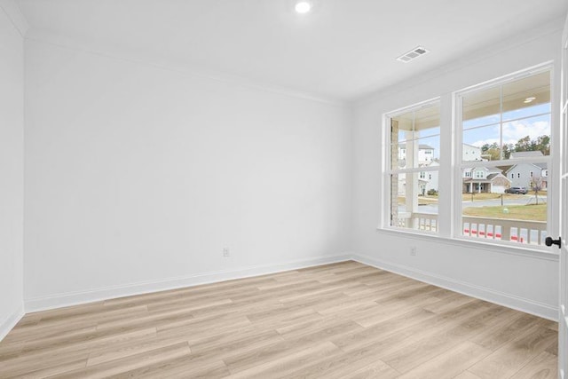 spare room with crown molding and light wood-type flooring