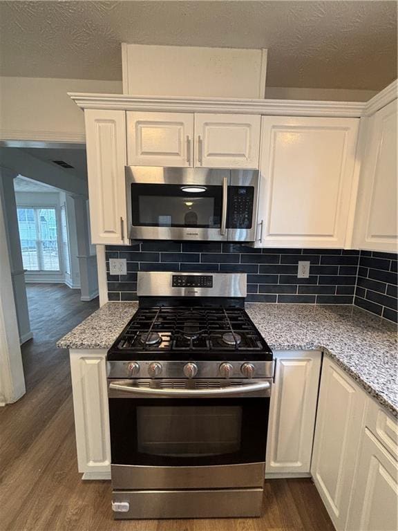 kitchen with white cabinets, light stone countertops, stainless steel appliances, and dark wood-style flooring