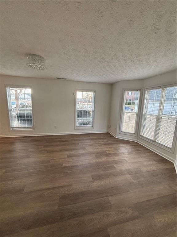 unfurnished room with dark wood finished floors, a textured ceiling, and baseboards