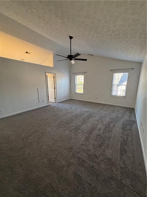 spare room with lofted ceiling, a healthy amount of sunlight, and dark colored carpet