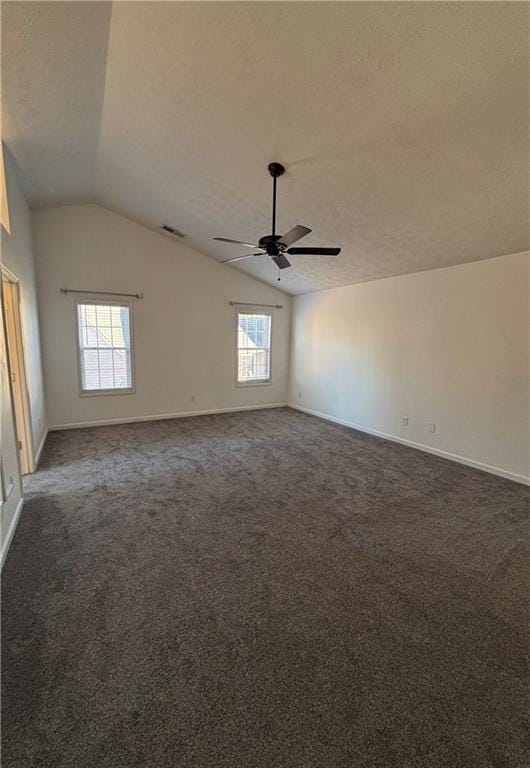 empty room featuring visible vents, vaulted ceiling, a textured ceiling, and dark colored carpet