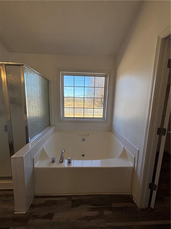 bathroom with a garden tub, a textured ceiling, wood finished floors, and a stall shower