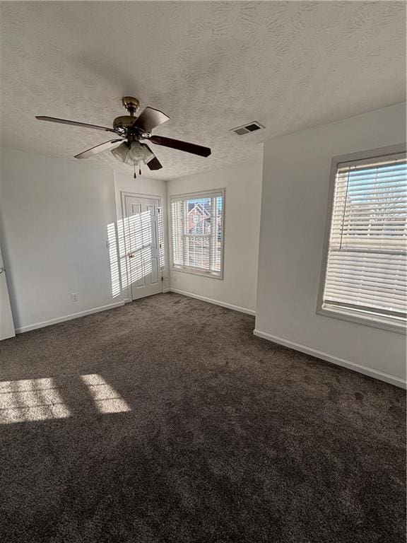 unfurnished room featuring dark carpet, a textured ceiling, and baseboards