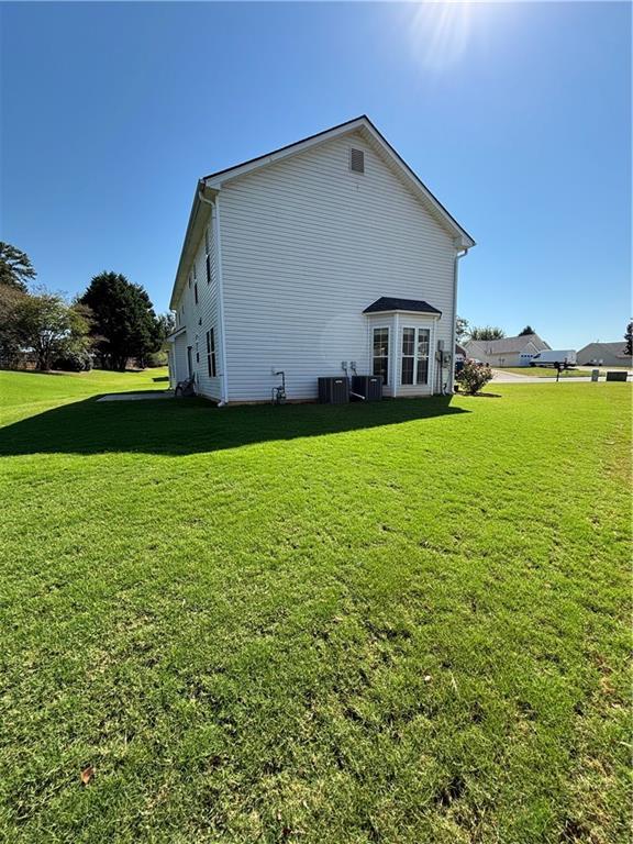 view of side of home featuring a lawn and central air condition unit