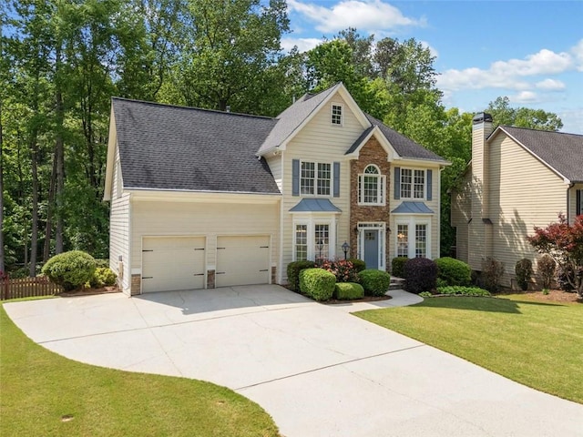colonial inspired home with a front lawn, stone siding, a shingled roof, an attached garage, and driveway