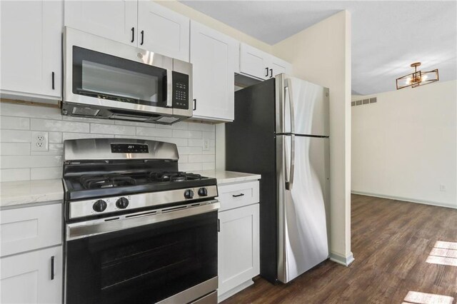 kitchen featuring dark wood-type flooring, light stone countertops, tasteful backsplash, white cabinetry, and stainless steel appliances