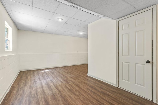 unfurnished room with a paneled ceiling and dark hardwood / wood-style flooring