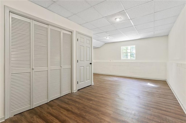 interior space with dark hardwood / wood-style floors, a drop ceiling, and a closet