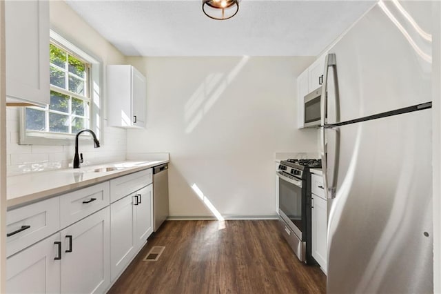 kitchen with backsplash, dark wood-type flooring, white cabinets, sink, and stainless steel appliances