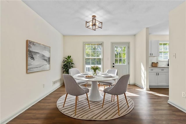 dining space with dark hardwood / wood-style floors and an inviting chandelier