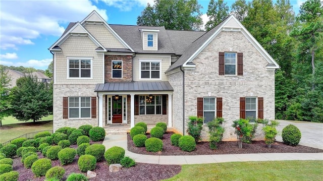 craftsman inspired home featuring brick siding, covered porch, a standing seam roof, and a shingled roof