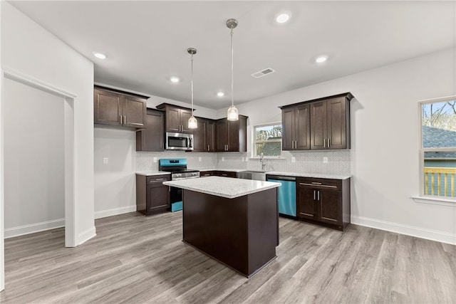 kitchen with dark brown cabinets, appliances with stainless steel finishes, a sink, and light wood-style floors