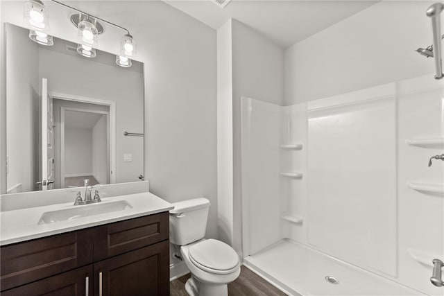 bathroom with a shower, wood finished floors, vanity, and toilet