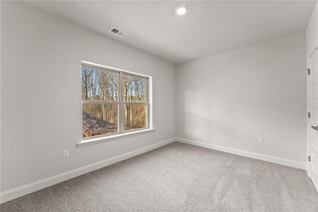carpeted spare room featuring visible vents and baseboards