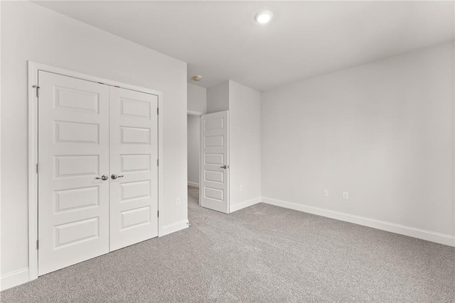 unfurnished bedroom with carpet, a closet, and baseboards