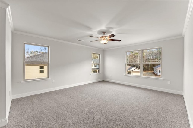 carpeted empty room with baseboards, ceiling fan, visible vents, and crown molding