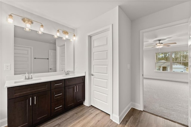full bathroom with double vanity, baseboards, a sink, and wood finished floors