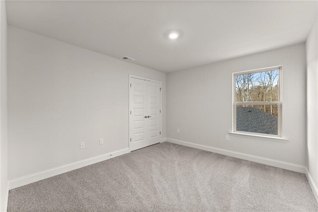 carpeted spare room with baseboards and visible vents