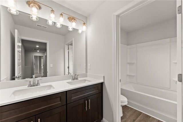 bathroom featuring visible vents, a sink, toilet, and double vanity