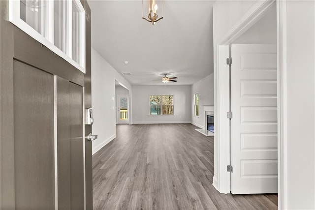 entrance foyer with ceiling fan, baseboards, wood finished floors, and a glass covered fireplace