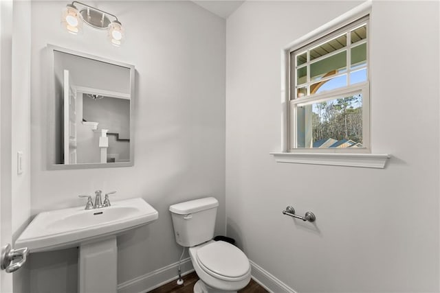 bathroom featuring toilet, baseboards, a sink, and wood finished floors