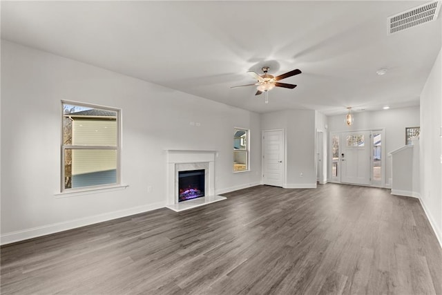 unfurnished living room with baseboards, a fireplace, visible vents, and wood finished floors