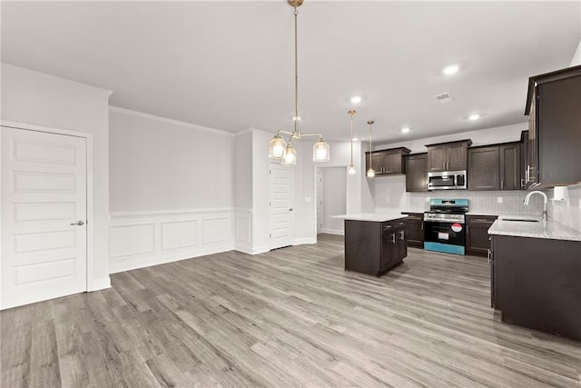 kitchen with light wood-style flooring, dark brown cabinetry, stainless steel appliances, a sink, and a center island